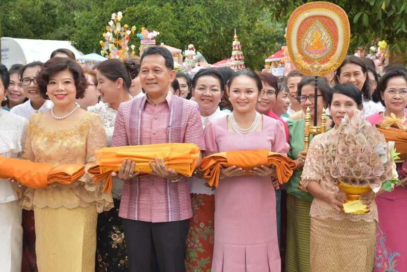 参加泰国佛教卡提那法会的人员在户外手持僧袍和法器