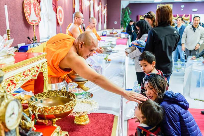 A Buddhist monk blesses a child during a merit-making ceremony in a Thai Buddhist celebration
